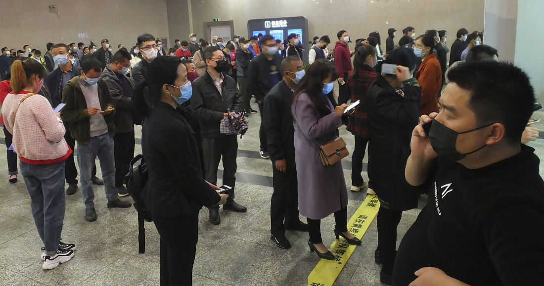 Viajeros hacen fila para comprar boletos de tren en Yichang, provincia de Hubei, China, miércoles 25 de marzo de 2020. Foto: Chinatopix vía AP