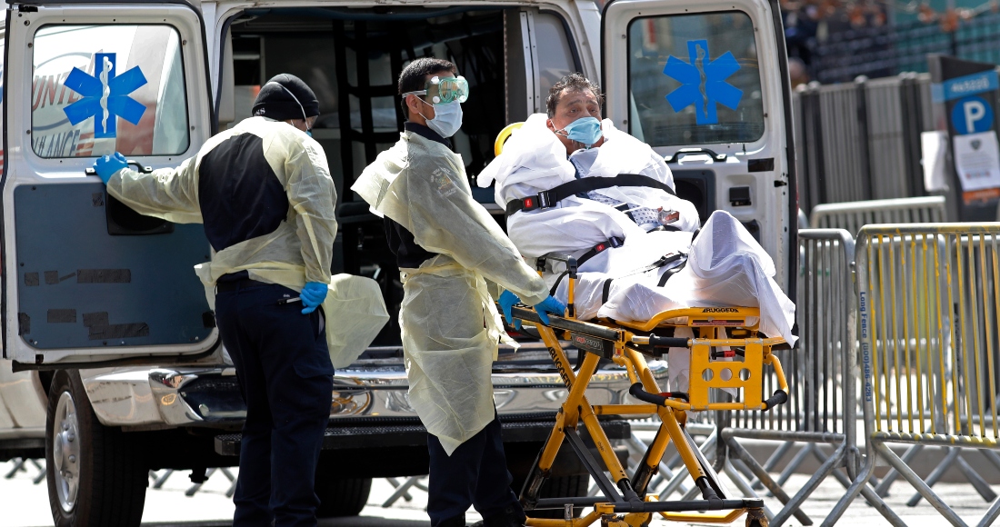 Médicos atienden a un paciente mientras esperan otra ambulancia afuera del Hospital Elmhurst, en Nueva York.