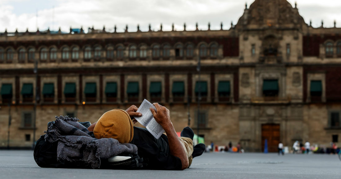 Un hombre lee un libro frente a Palacio Nacional el 7 de agosto de 2020 en Ciudad de México (México).