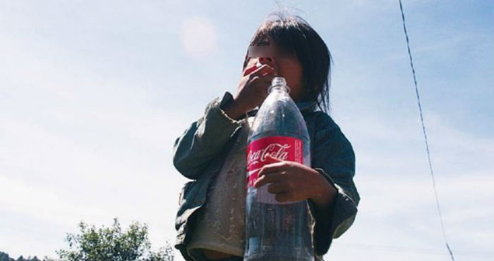 Una niña con un envase de Coca-Cola.