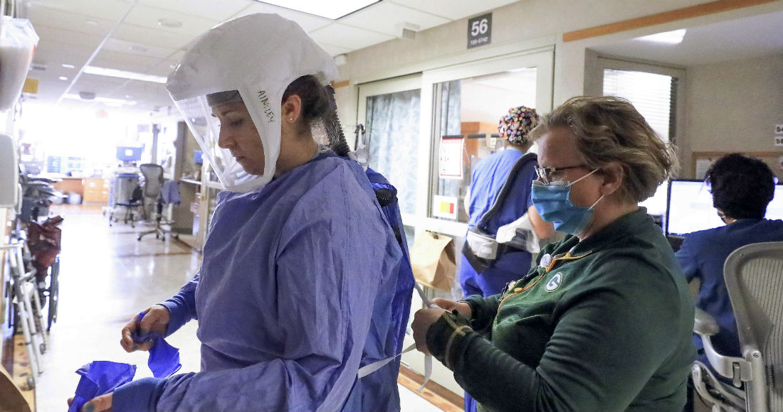 En esta fotografía del 5 de noviembre de 2020, Deb Dalsing, enfermera de la unidad de COVID-19 del hospital UW Health, ayuda a la enfermera Ainsley Billesbach con su equipo de protección, en Madison, Wisconsin.