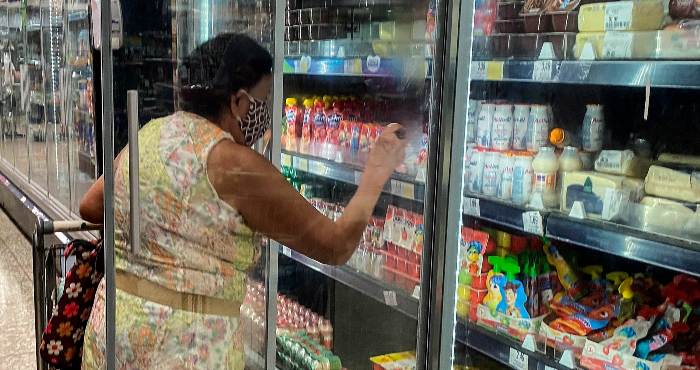 Una mujer compra alimentos en el refri del supermercado.