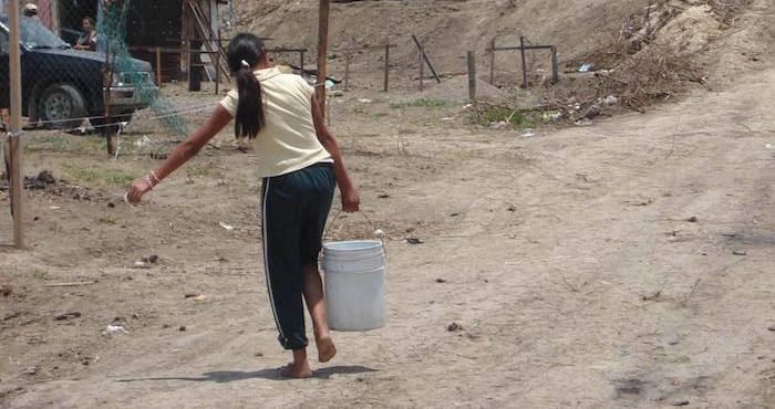 Una mujer acarrea una cubeta de agua en Guerrero.