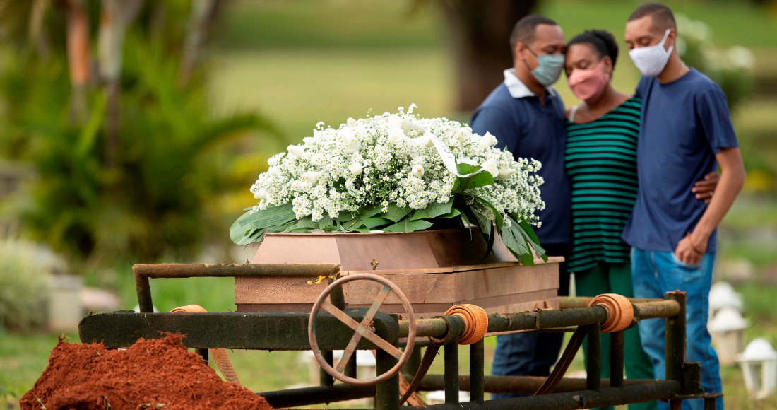 Un grupo de personas asiste al entierro de un ser querido víctima de COVID-19 hoy, en el cementerio Campo da Esperança, en la ciudad de Brasilia (Brasil).