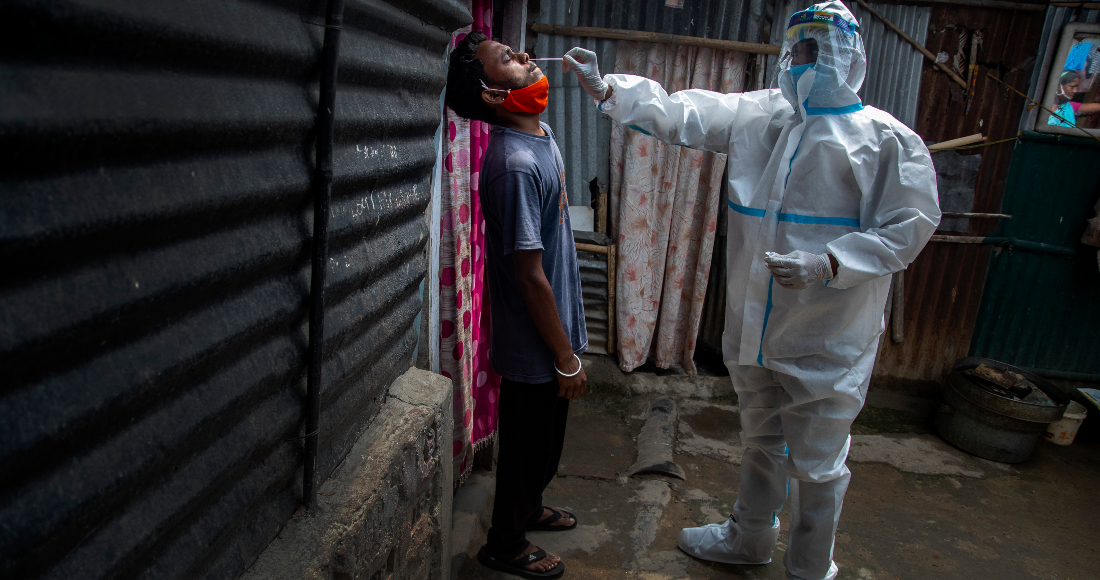 Un trabajador de la salud, con un traje de protección, toma una muestra nasal a un hombre para una prueba de COVID-19, en una barriada pobre de Gauhati, en el estado de Assam, India, el 17 de mayo de 2021.