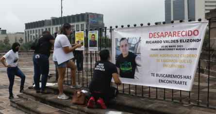 Personas cuelgan carteles con fotos de sus desaparecidos en el norte de México.