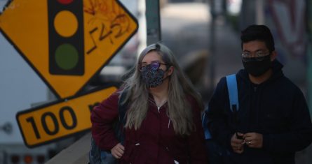 Jóvenes caminan sobre avenida Constituyentes, en la Ciudad de México, portando cubrebocas personalizados.