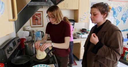 Las estudiantes Sophia Pavlenko, a la izquierda, de Rusia, y Masha Novikova, de Ucrania, preparan blinis, crepas al estilo de Europa del Este, para vender a sus compañeros en el United World College y recaudar fondos para apoyar a los ucranianos afectados por la guerra, en Montezuma, Nuevo México, el domingo 12 de marzo de 2022.