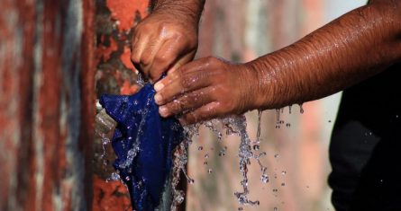 Un trabajador del Servicio de Agua y Alcantarillado de Cuernavaca intenta controlar el agua que sale de una tubería.