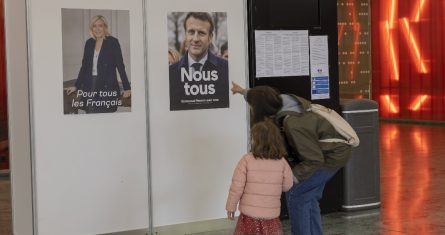 Un votante muestra a su hija los carteles electorles de los candidatos a la Presidencia francesa.