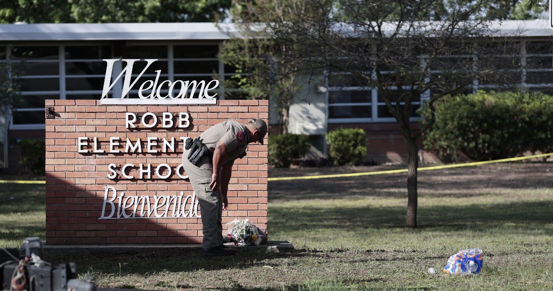 Un Policía Estatal De Texas Coloca Flores Al Pie Del Letrero De La Escuela Primaria Robb Mientras Los Investigadores Continúan Trabajando En La Escena De Un Tiroteo Masivo En La Escuela Que Mató a Niños Y Dos Adultos Según El Gobernador De Texas Greg Abbott En Uvalde Texas Estados Unidos De Mayo De