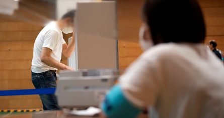 Una trabajadora de la administración electoral local mira mientras un votante prepara su boleta en las elecciones parlamentarias en un centro de electoral el domingo 10 de julio de 2022 en Tokio.