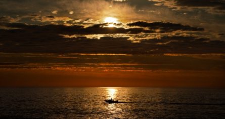 A primera hora de la mañana, un pescador deportivo navega sobre el mar en calma de camino a los bancos de pesca de lubina rayada frente a la costa de Kennebunkport, Maine, el 7 de julio de 2022.